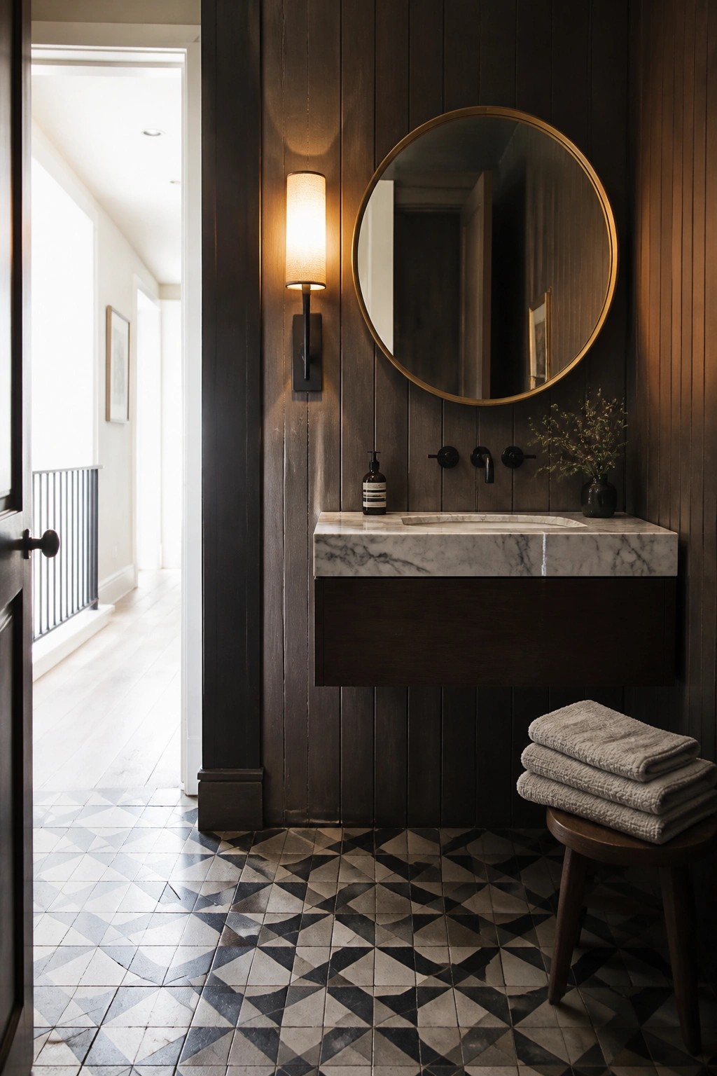 A bathroom with dark wood vertical paneling, a floating marble vanity, a round mirror, and a wall sconce.