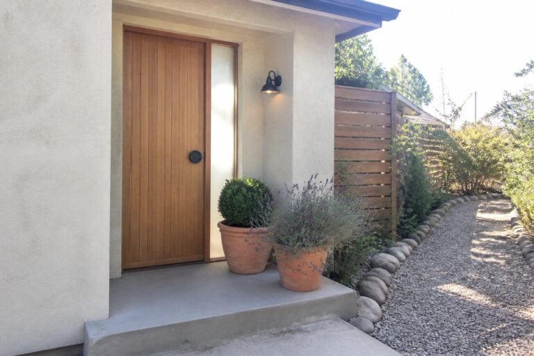 Modern wooden door with terracotta pots, lavender, and gravel path at home entrance