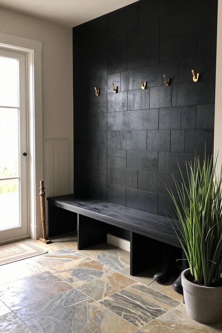 A black wood plank accent wall with gold hooks above a built-in black bench in a tiled entryway next to a door.