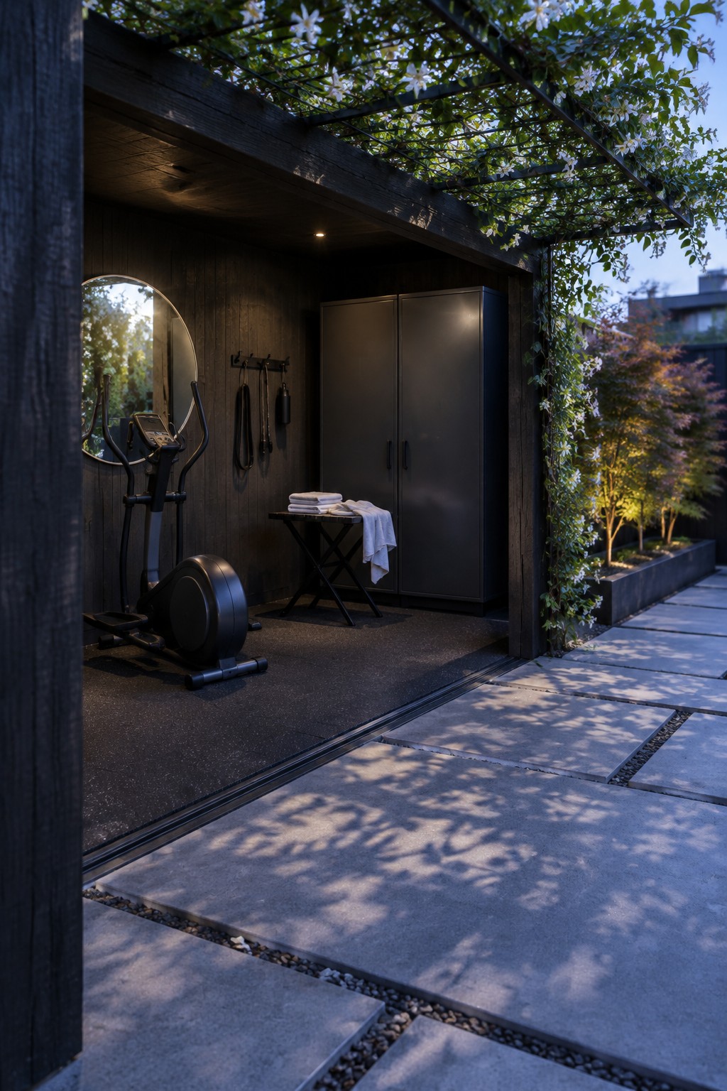 Modern dark wood outdoor gym with elliptical machine, black cabinets and flowering pergola.